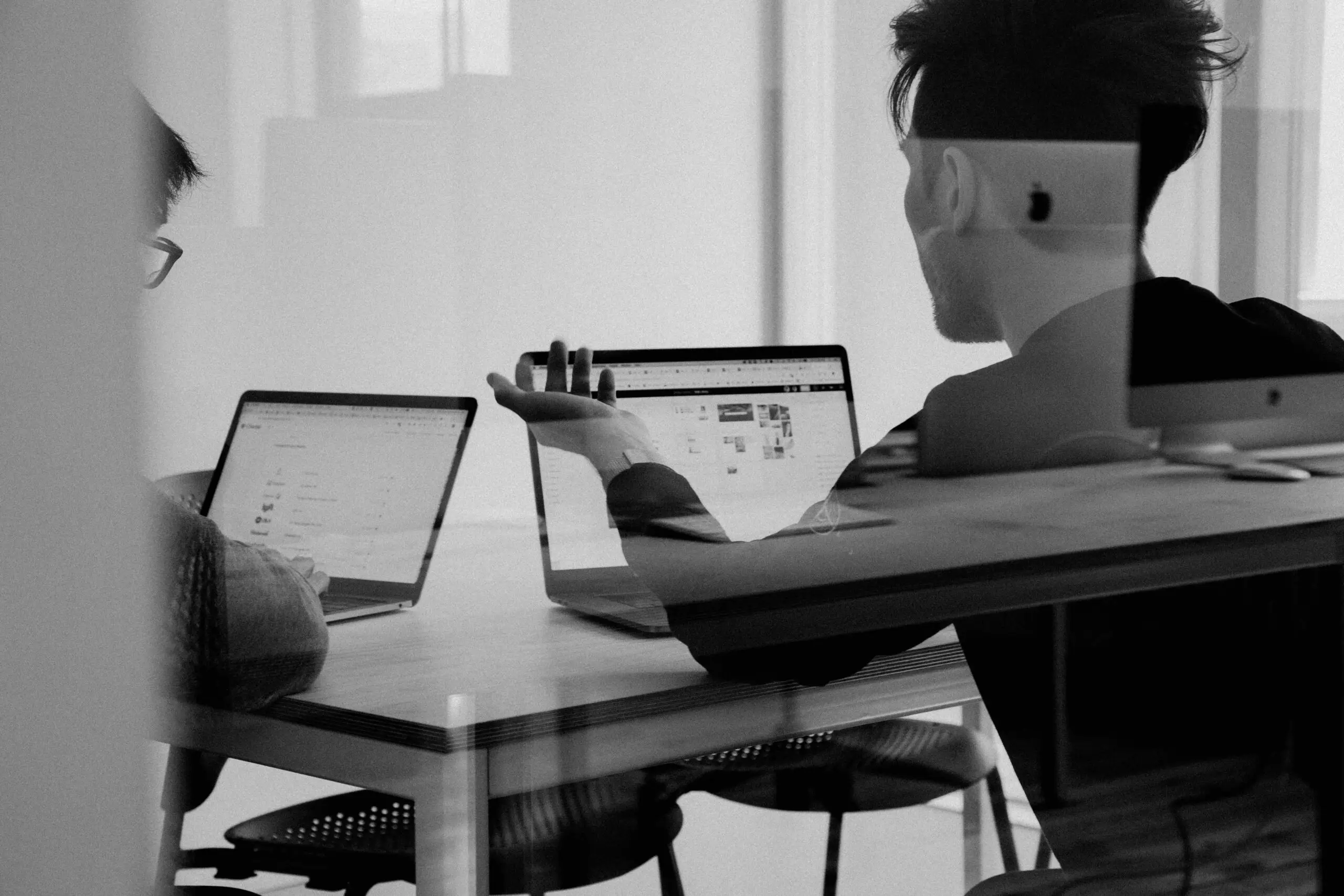 Zwei Personen besprechen ein Webprojekt an Laptops im Büro